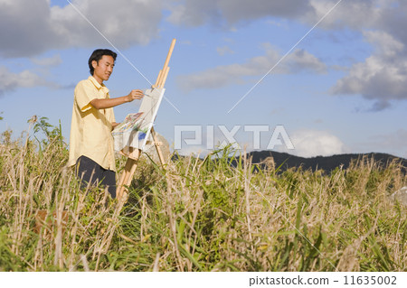 Asian man painting at easel outdoors Asian man painting at easel outdoors 11635002