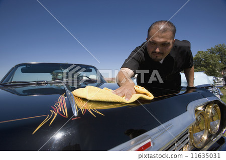Hispanic man buffing show car 11635031