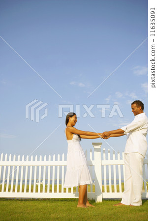 Couple holding hands next to fence 11635091