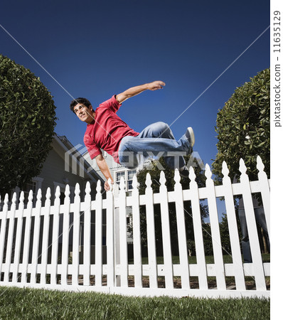 Hispanic man jumping over fence 11635129