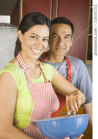 Hispanic couple mixing batter in kitchen Hispanic couple mixing batter in kitchen 11635151