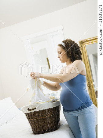 Pregnant African woman folding laundry 11635171