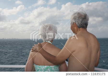 Senior Asian couple looking out over water Senior Asian couple looking out over water 11635173