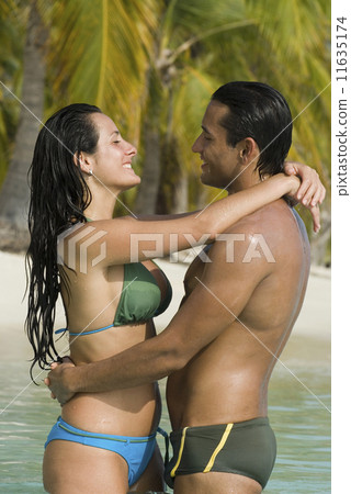 Hispanic couple hugging in water 11635174