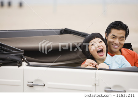 Asian couple laughing in convertible 11635211