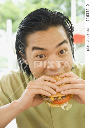 Asian man eating hamburger Asian man eating hamburger 11635240