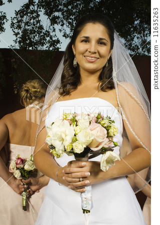 Hispanic bride holding bouquet 11635263