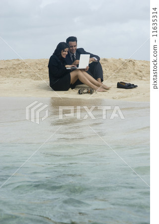 Hispanic businesspeople working at beach 11635314