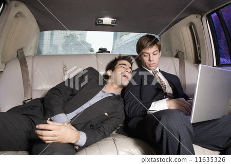 Hispanic businessman sleeping on coworker in limousine Hispanic businessman sleeping on coworker in limousine 11635326
