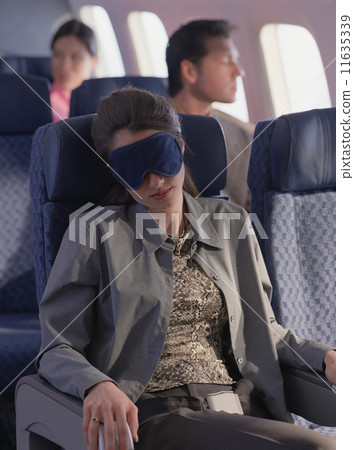 Young woman sleeping on airplane with eye mask 11635339