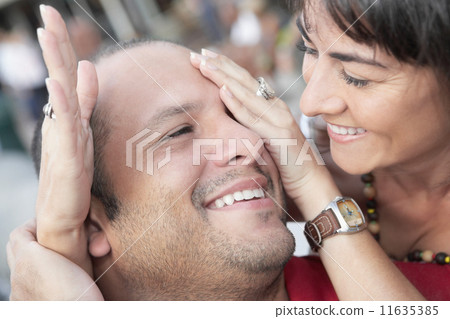Hispanic woman covering husband's eyes Hispanic woman covering husband's eyes 11635385