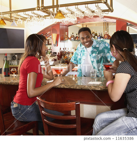 Multi-ethnic women sitting at bar Multi-ethnic women sitting at bar 11635386