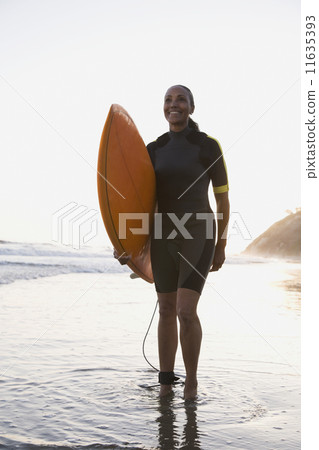 Mixed Race woman holding surfboard Mixed Race woman holding surfboard 11635393
