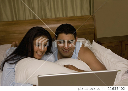 Multi-ethnic couple looking at laptop 11635402