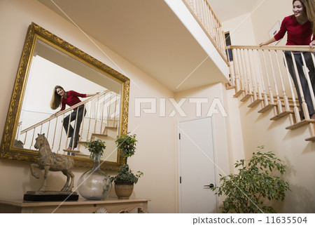 Hispanic woman looking in mirror from stairs 11635504