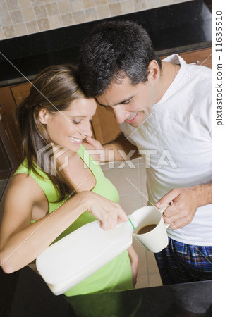 Hispanic woman pouring milk in husband's coffee 11635510