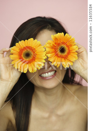 Asian woman holding flowers over eyes Asian woman holding flowers over eyes 11635584