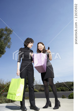 Two Asian women looking in shopping bag Two Asian women looking in shopping bag 11635602
