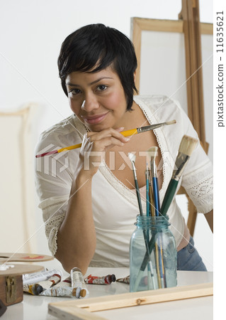 Portrait of Hispanic female artist holding paintbrush Portrait of Hispanic female artist holding paintbrush 11635621