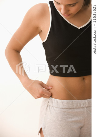 Teenager pinching fat on side of stomach 11635625