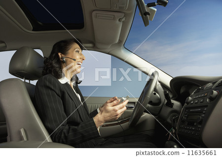 Businesswoman driving and talking on a headset Businesswoman driving and talking on a headset 11635661
