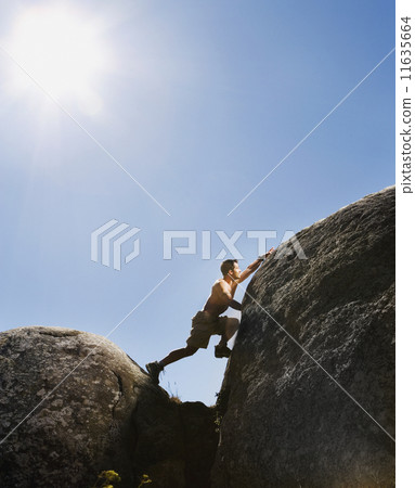 Pacific Islander man climbing rock formations 11635664
