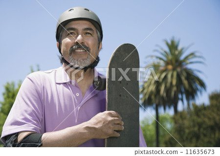 Hispanic man holding skateboard 11635673