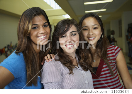 Multi-ethnic teenaged girls hugging in school hallway 11635684