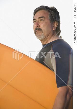 Hispanic man holding surfboard 11635698