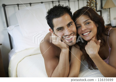 Hispanic couple laying on bed 11635699
