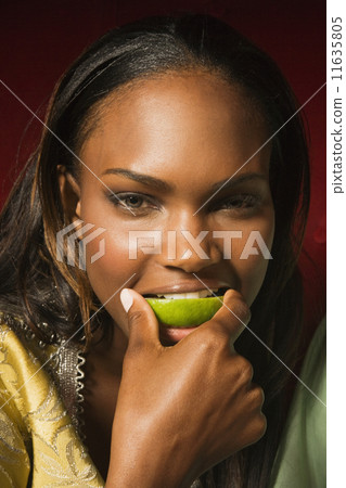 African woman biting lime slice 11635805