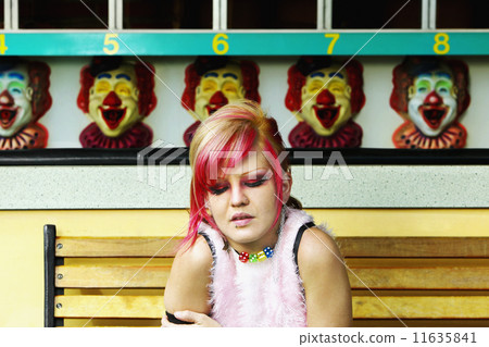 Young Hispanic punk female sitting in front of carnival booth 11635841