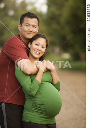 Pregnant Asian couple hugging Pregnant Asian couple hugging 11635886