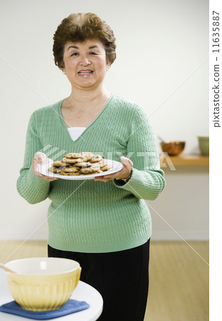 Senior Asian woman holding plate of cookies 11635887