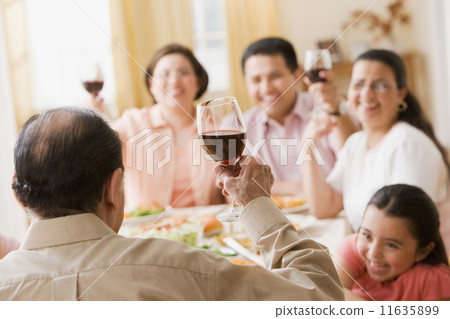 Hispanic family toasting at dinner table 11635899