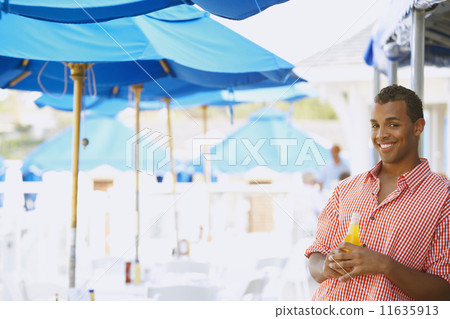 Hispanic man with drink at beach 11635913