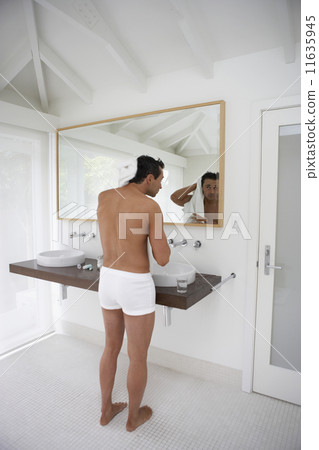 Man wearing underwear and drying hair in bathroom 11635945