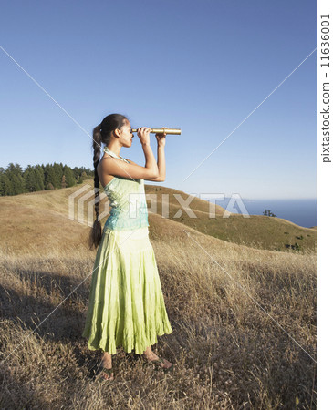 Woman using telescope to view distant hills 11636001