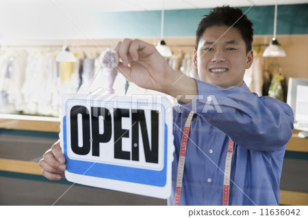 Asian drycleaner putting up open sign Asian drycleaner putting up open sign 11636042