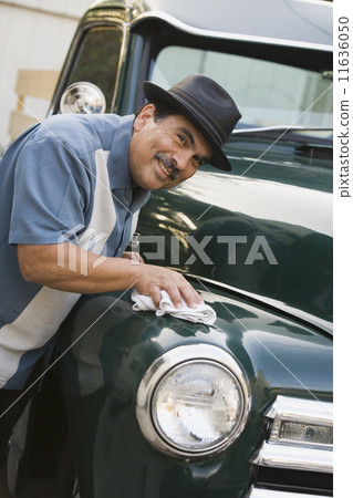 Middle-aged Hispanic man waxing classic car 11636050