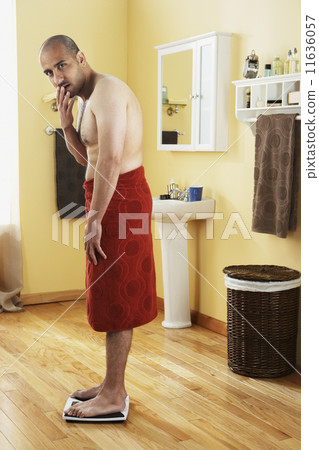 Middle Eastern man standing on scale 11636057