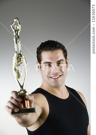 Hispanic man holding sport trophy 11636073