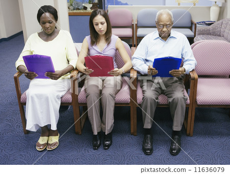 Group of people reading paperwork while sitting in waiting room 11636079
