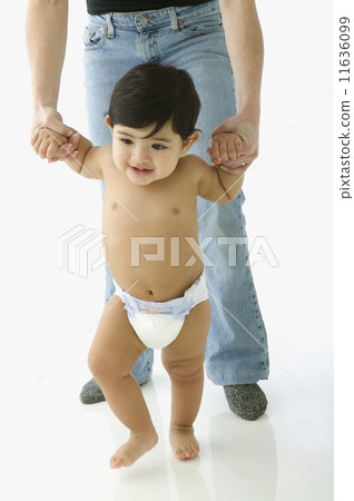 Toddler boy in diaper walking with help of parent 11636099