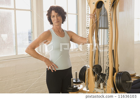 Senior woman standing next to exercise equipment 11636103