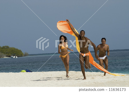 Hispanic friends flying kite at beach Hispanic friends flying kite at beach 11636173