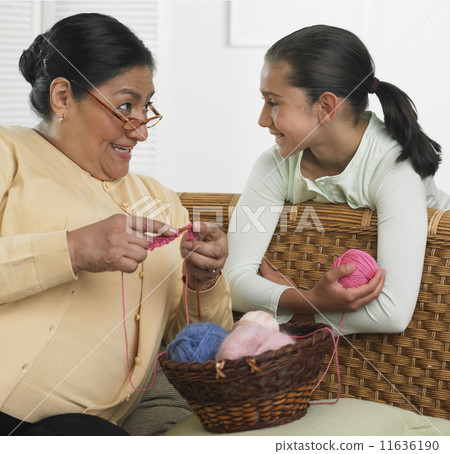 Hispanic grandmother and granddaughter with knitting supplies 11636190