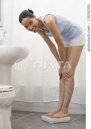 African woman standing on bathroom scale 11636203
