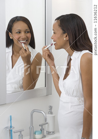 Pregnant African woman applying lipstick in mirror Pregnant African woman applying lipstick in mirror 11636212