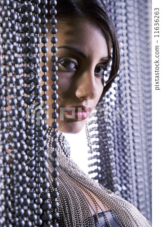 Portrait of Hispanic woman in beaded curtain 11636263